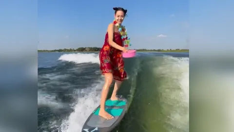 สาดน้ำยังไงให้โลกจำ "แซมมี่ เคาวเวลล์" นุ่งผ้าถุงลายดอกถือขันน้ำ พร้อมลีลาเล่นเซิร์ฟ