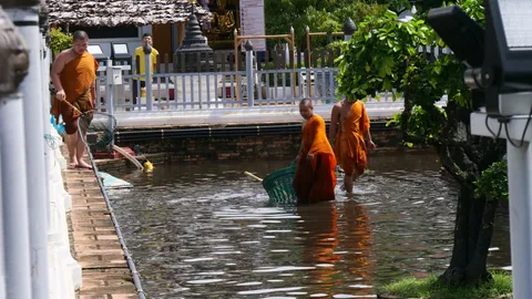 พระ-เณร ช่วยเร่งเปิดทางระบาย "น้ำท่วมขัง" รอบ "พระธาตุเจดีย์หลวง"