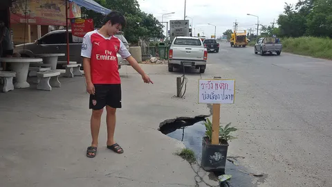 ติดป้ายประชด 'ระวังตก-บ่อเลี้ยงปลา' น้ำเซาะถนนเป็นหลุมกว่าปี ไร้แก้ไข