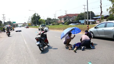 หนุ่มใจดีกางร่มบังแดดให้สาว ขี่ จยย.ชนเก๋ง นอนเจ็บรอกู้ภัยช่วย