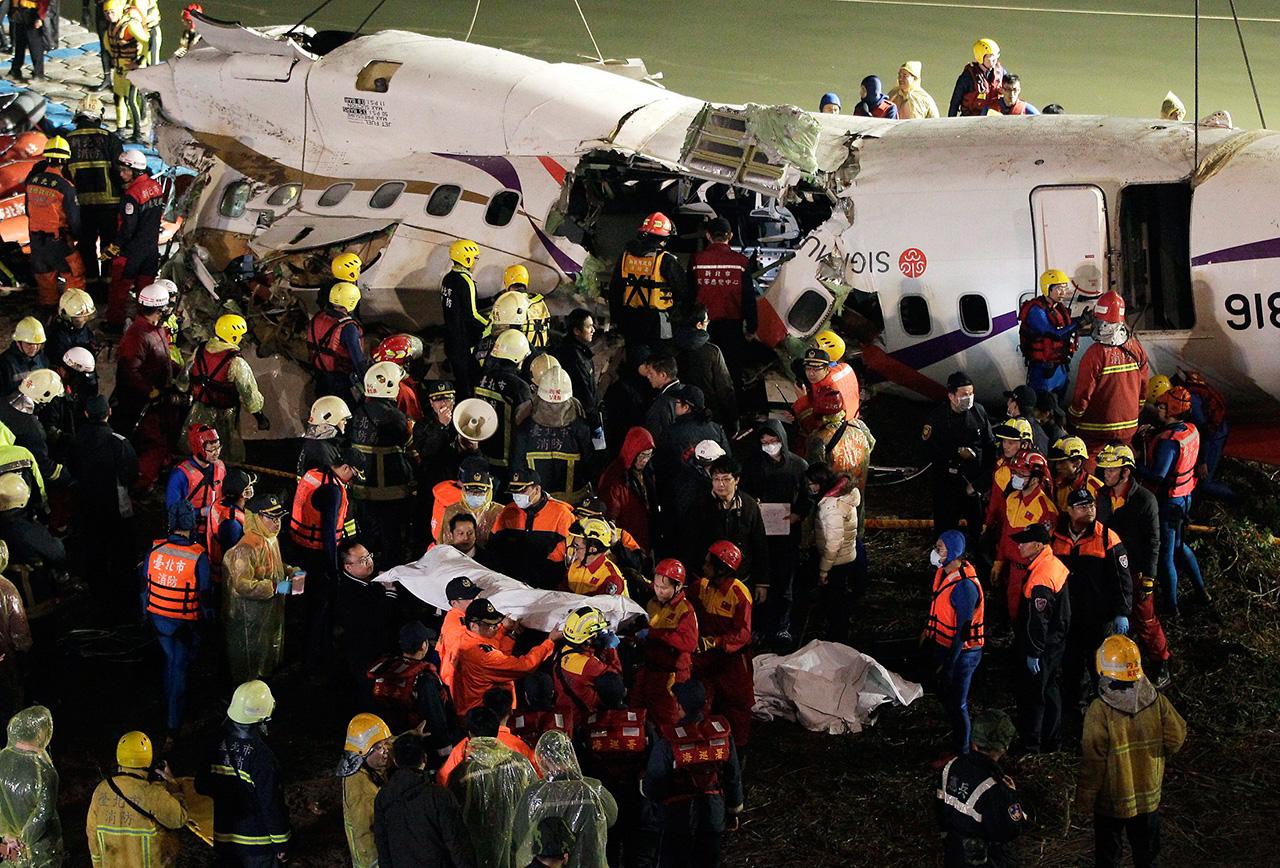 เจ้าหน้าที่ลำเลียงศพผู้เสียชีวิตออกมาจากซากเครื่องบิน (ภาพ: REUTERS)