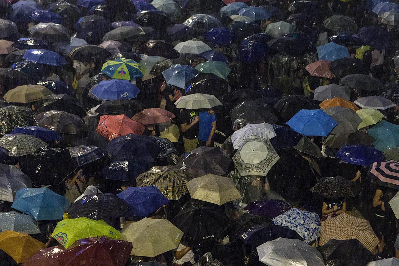 ผู้ชุมนุมกางร่มกันฝนที่ตกลงมาอย่างหนักเมื่อคืนวันอังคาร
