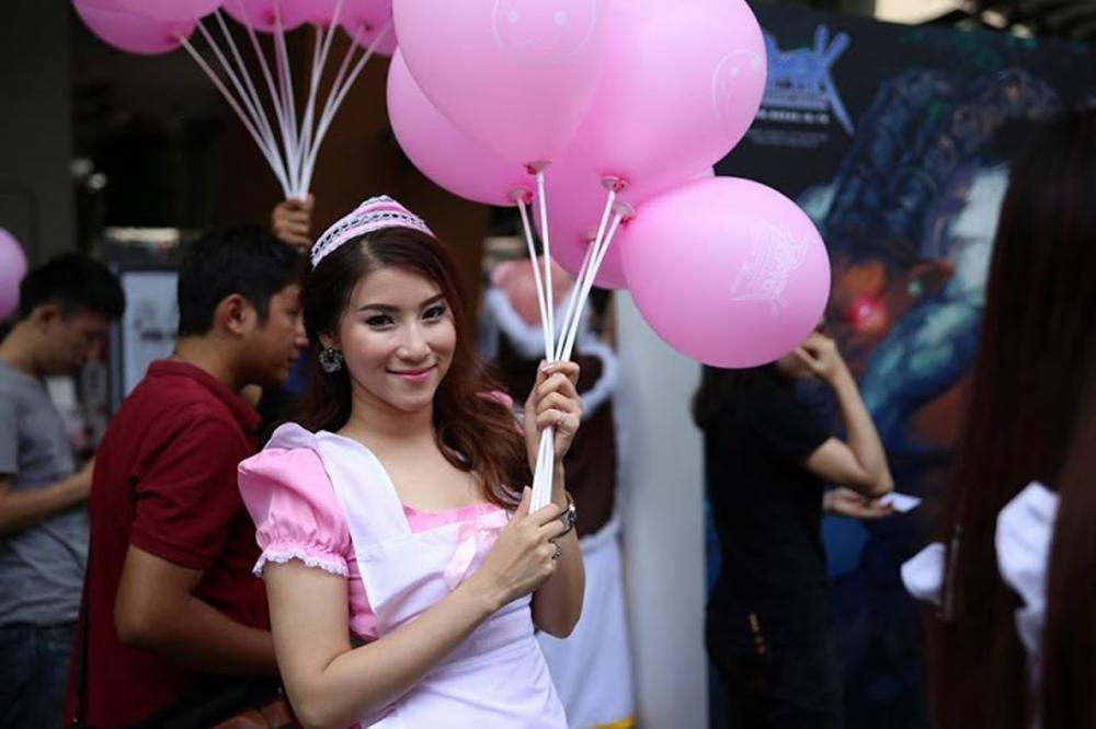 พริตตี้สาวยืนแจกลูกโป่งให้กับผู้เล่นที่มาร่วมงาน