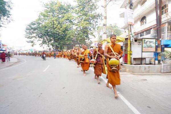 พระสงฆ์เดินเข้าตัวเมือง และรับบิณฑบาตจากชาวบ้านตามเส้นทางที่ผ่านไป.