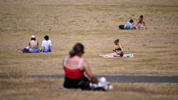 ผู้คนออกมาอาบแดด บนสนามหญ้าในสวนสาธารณะกรีนวิช ในกรุงลอนดอน เมื่อ 16 ก.ค. 65  ขณะที่สหราชอาณาจักรกำลังเผชิญกับสภาพอากาศร้อนจัด จากอิทธิพลคลื่นความร้อน