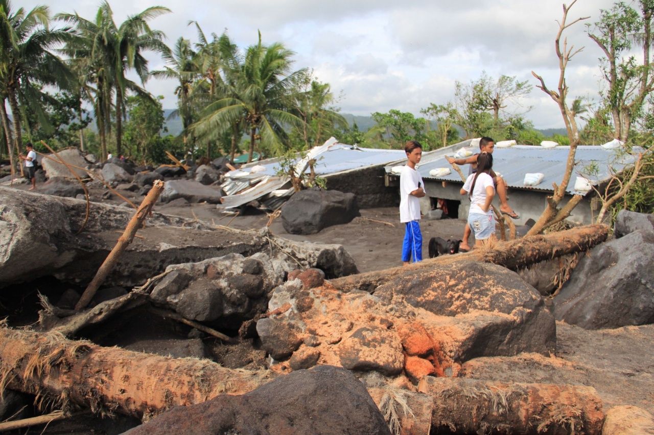 ชาวฟิลิปปินส์ยืนดูความเสียหายจากไต้ฝุ่นโคนี ทำให้เกิดฝนตกหนักจนเกิดน้ำป่าพัดหินก้อนใหญ่และเถ้าถ่านภูเขาไฟ จากภูเขาไฟมายอนลงมาทับถมในหมู่บ้านกุยโนบาตัน จังหวัดอัลเบย์ 