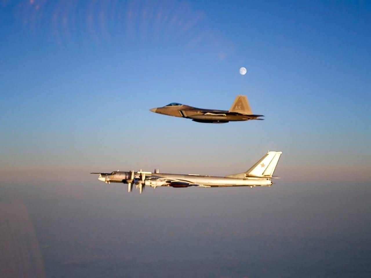 เครื่องบินตู-95 ที่มีเครื่องบินขับไล่เอฟ-22 ตามบินประกบขณะเข้าใกล้น่านฟ้าสหรัฐฯ ภาพจากวิกิพีเดีย