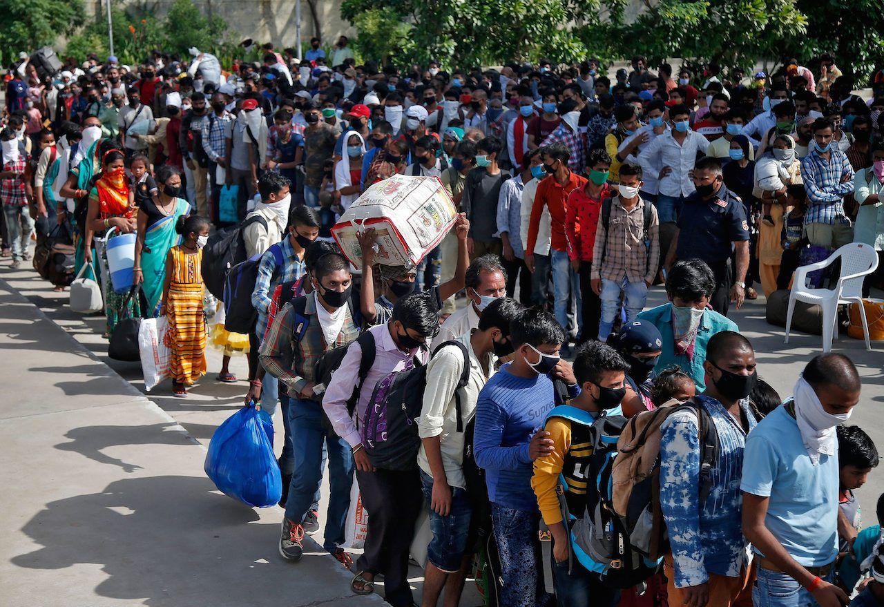 แรงงานย้ายถิ่นจำนวนมหาศาลมาเข้าคิวขึ้นรถบัสไปสถานีรถไฟในรัฐอุตตรประเทศ หลังรัฐบาลเริ่มให้บริการรถไฟอีกครั้งอย่างจำกัด