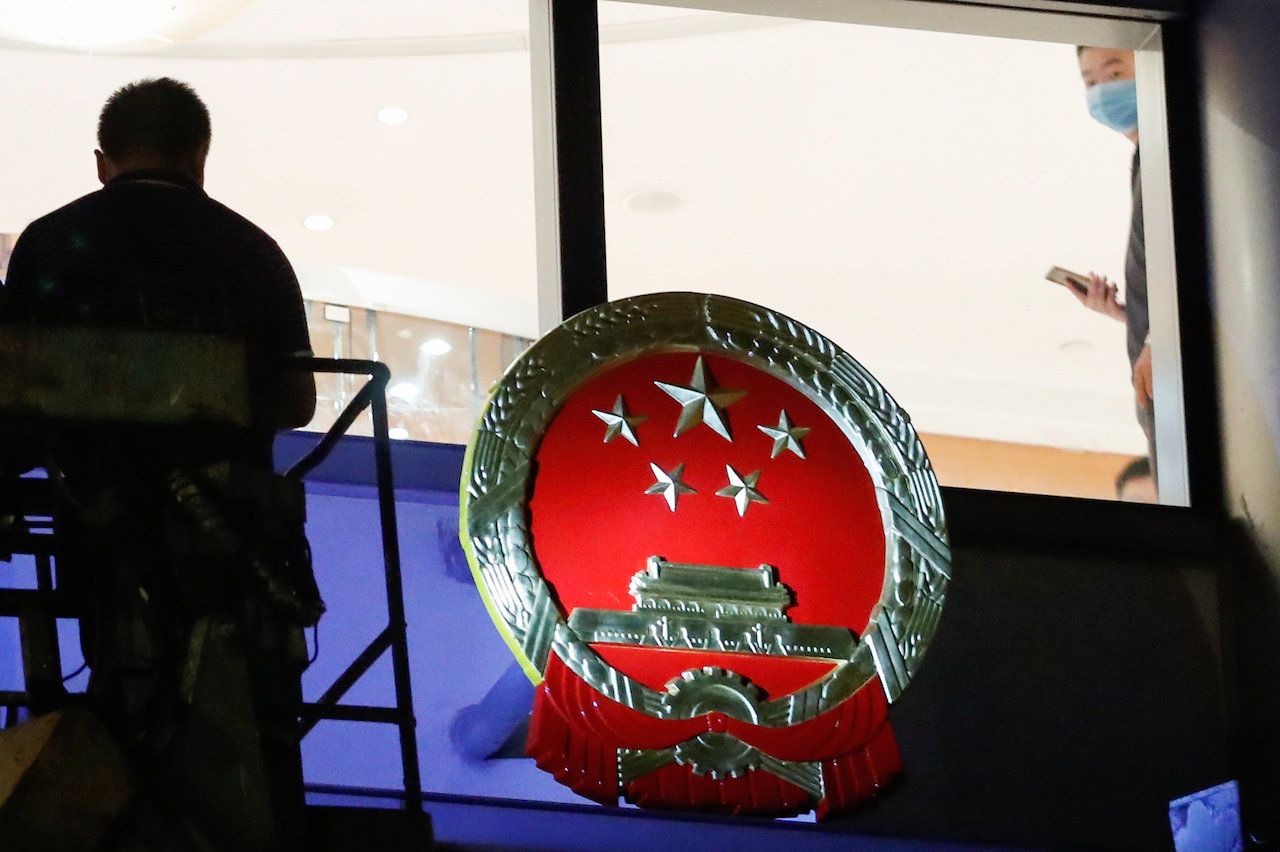 คนงานนำป้ายสัญลักษณ์แห่งชาติจีนมาติดที่หน้าโรงแรมเมโทรพาร์ค ในเขต คอสเวย์ เบย์ ของฮ่องกง เมื่อเที่ยงคืนวันที่ 7 ก.ค. 2563 โดยเชื่อว่าโรงแรมแห่งนี้จะถูกใช้เป็นสำนักงานชั่วคราว ของสำนักงานความมั่นคงแห่งชาติที่จีนเข้ามาก่อตั้งในฮ่องกง