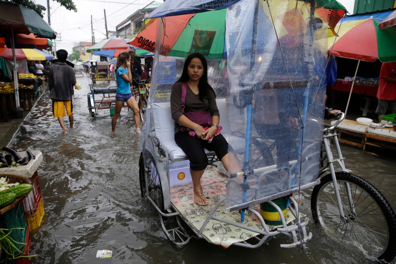 หญิงฟิลิปปินส์นั่งบนรถสามล้อ เลี่ยงน้ำท่วม ชานกรุงมะนิลา จากพายุโซนร้อน ‘​Nesat’ เมื่อ 27 ก.ค.60