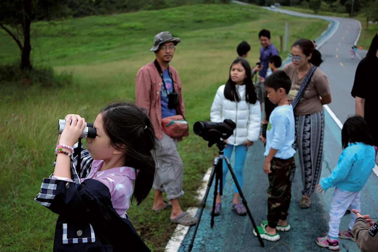 การดูนกเป็นดังประตูสู่การเรียนรู้ธรรมชาติสำหรับเด็ก  เมื่อมีผู้นำหรือพี่เลี้ยงดูนกที่มีประสบการณ์  สามารถเชื่อมโยงนกกับความสัมพันธ์ในระบบนิเวศ เด็กที่เล่นหรือใช้เวลากลางแจ้งในธรรมชาติมีแนวโน้มจะใส่ใจปกป้องสิ่งแวดล้อมเมื่อเติบโตขึ้น  (ภาพถ่าย: เอกรัตน์ ปัญญะธารา)