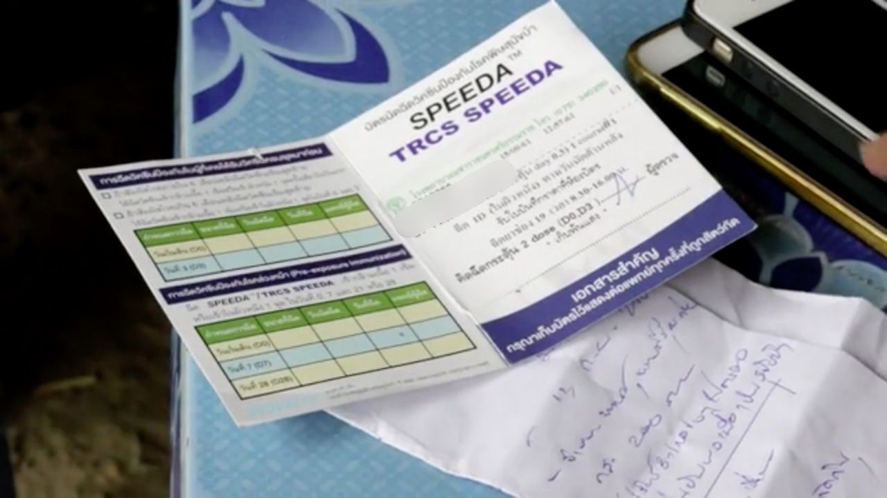 ชาวบ้านแสดงบัตรฉัดวัคซีนป้องกันโรคพิษสุนัขบ้านให้ผู้สื่อข่าวดู