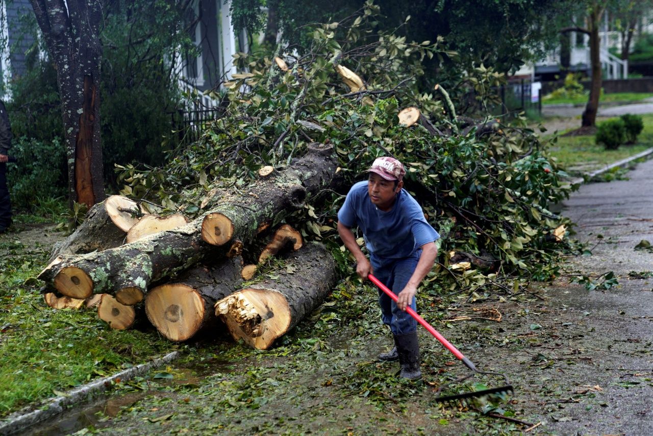 ชายคนหนึ่งตัดต้นไม้ที่หักโค่นลงมากีดขวางถนนในเมืองวิลมิงตัน