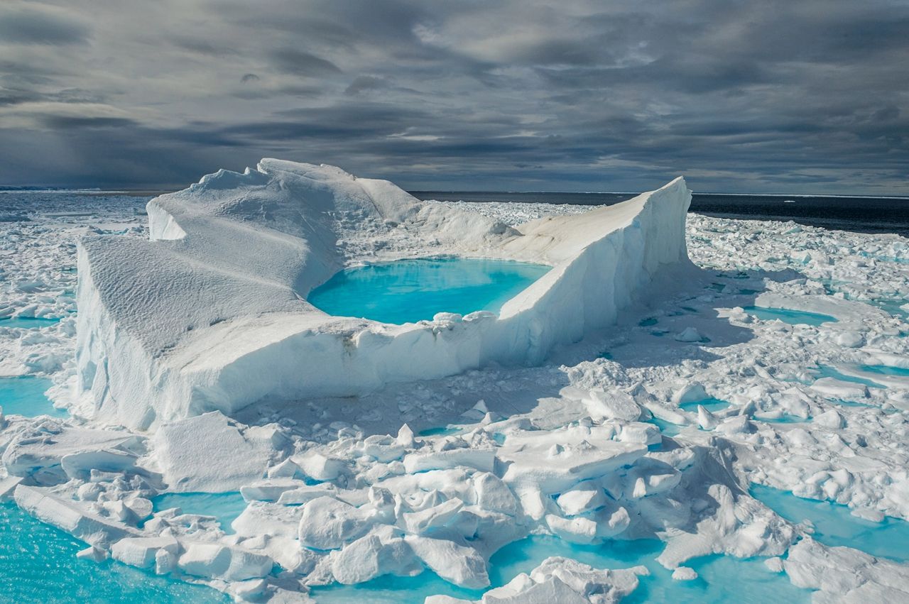 นอกชายฝั่งทางเหนือของเกาะแบฟฟิน ดวงอาทิตย์เดือนมิถุนายนพลิกโฉมผืนหิมะและน้ำแข็งให้กลายเป็นแอ่งน้ำสีเทอคอยส์กระจ่างใส พื้นที่น้ำแข็งทะเลที่คงอยู่ตลอดปีของอาร์กติก ซึ่งเป็นน้ำแข็งที่รอดจากฤดูน้ำแข็งละลายในหน้าร้อน กำลังหดตัวลงอย่างฮวบฮาบ