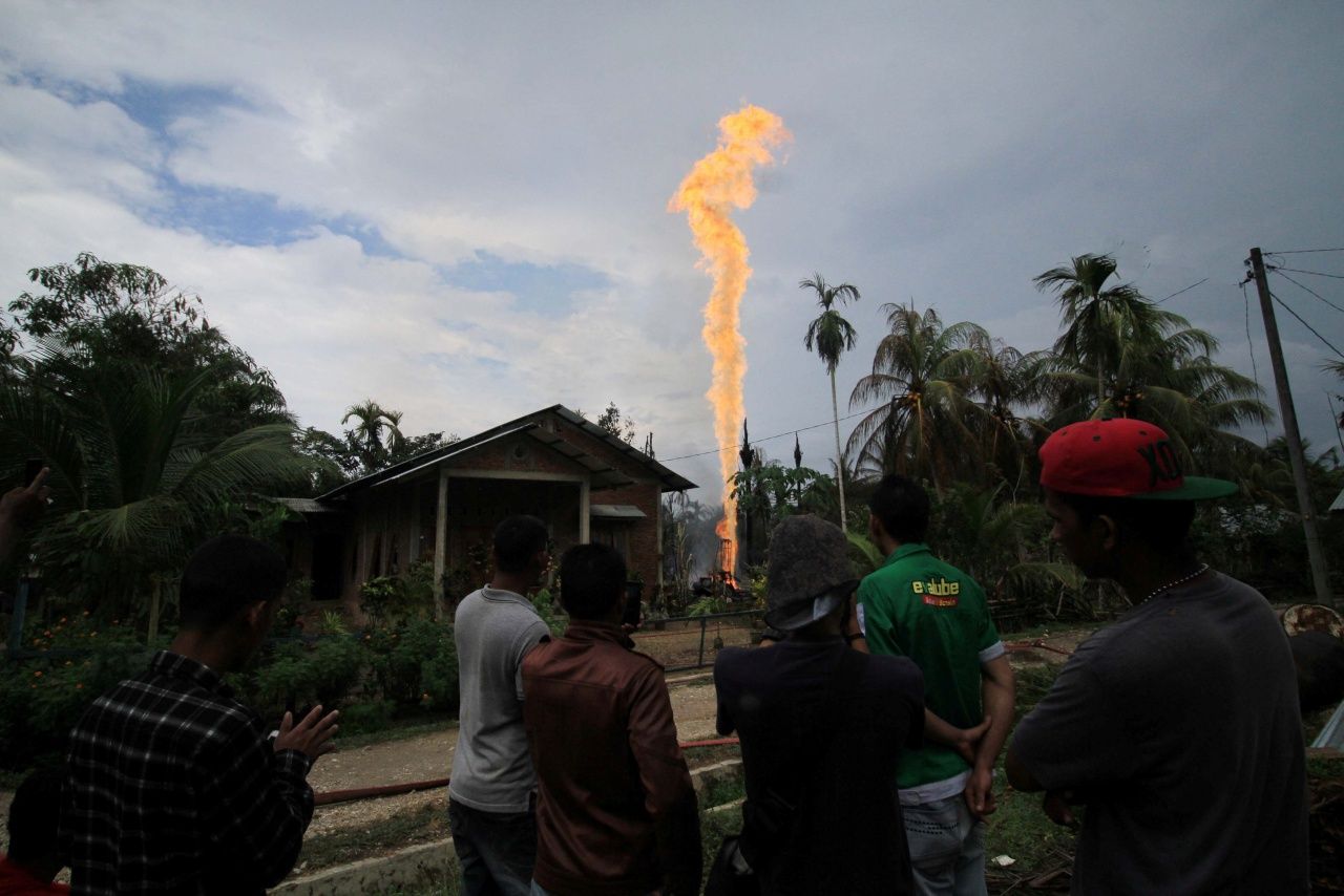 ชาวบ้านมุงดูเสาเพลิงที่พุ่งขึ้นมาจากบ่อน้ำมัน