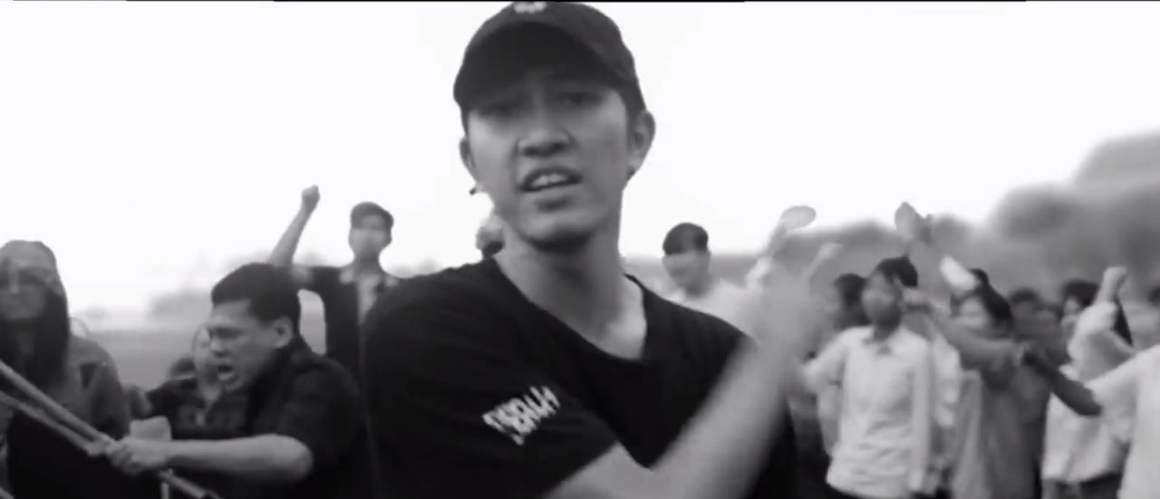 ผู้ชายริมสุดกำลังใช้เก้าอี้ฟาดๆ ศพในเอ็มวี ประเทศกูมี 