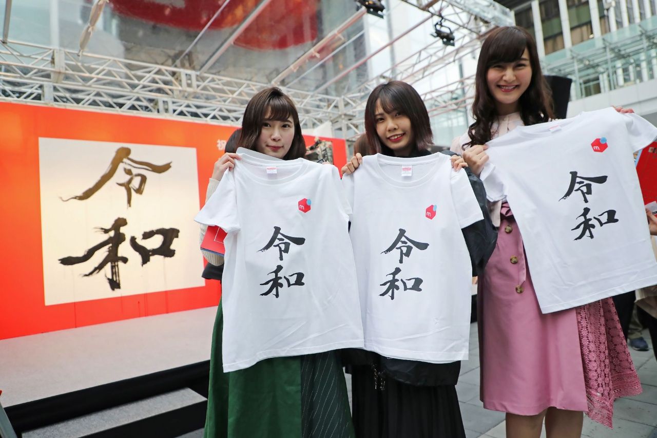 สาวๆ ชาวญี่ปุ่นถือเสื้อที่มีคำว่า เรวะ ซึ่งเป็นชื่อรัชสมัยใหม่ของญี่ปุ่น