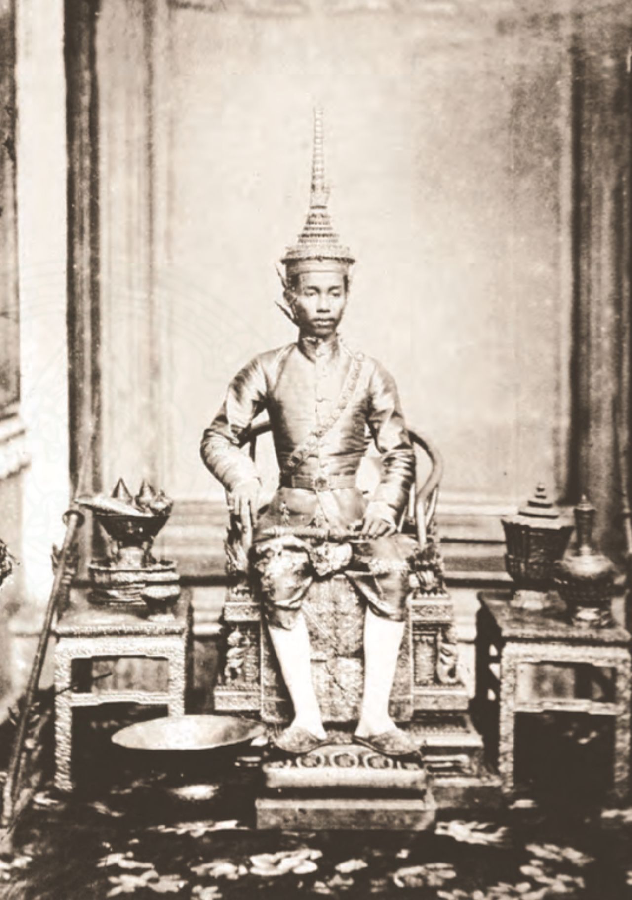 พระบาทสมเด็จพระจุลจอมเกล้าเจ้าอยู่หัว ประทับพระที่นั่งพุดตานกง โต๊ะเคียงทอดเครื่องราชูปโภค ในงานพระราชพิธีบรมราชาภิเษกครั้งแรก  พ.ศ 2411