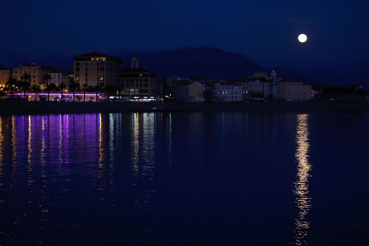 แสงไฟจากเมืองและจากพระจันทร์เต็มดวงสะท้อนกับผืนน้ำบนเกาะคอร์สิกา ในทะเลเมดิเตอร์เรเนียน