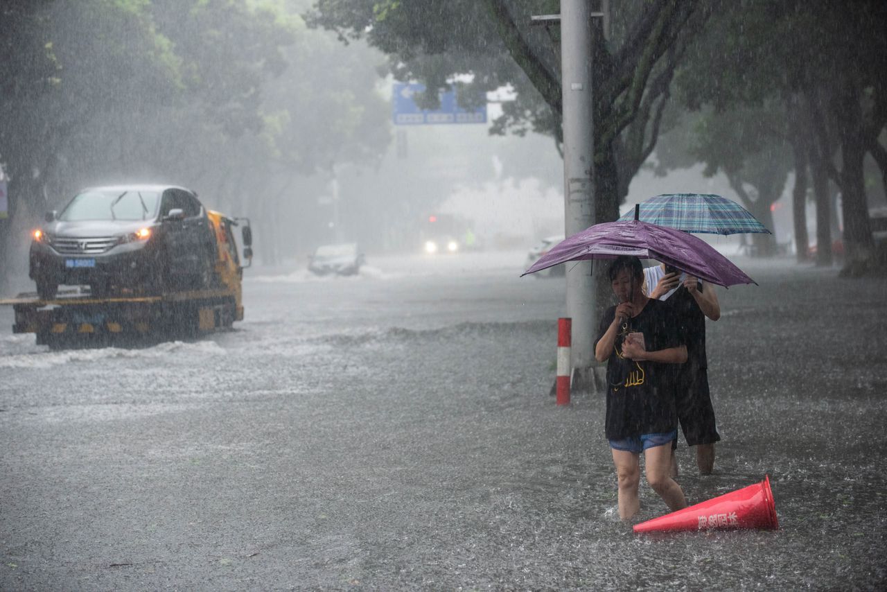 ชาวจีนเดินถือร่มลุยน้ำท่วมถนน ขณะเกิด ฝนตกหนัก ที่เมืองหนิงโป มณฑลเจ้อเจียง จากอิทธิพลซุปเปอร์ไต้ฝุ่น เลกิมา