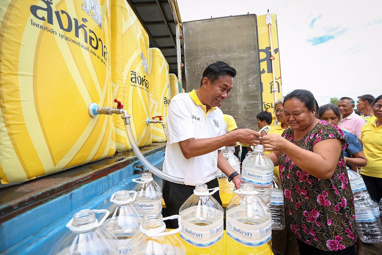 ชาวบ้านหลายคนมองขวดน้ำด้วยความดีใจได้รับน้ำสะอาดบริโภค.