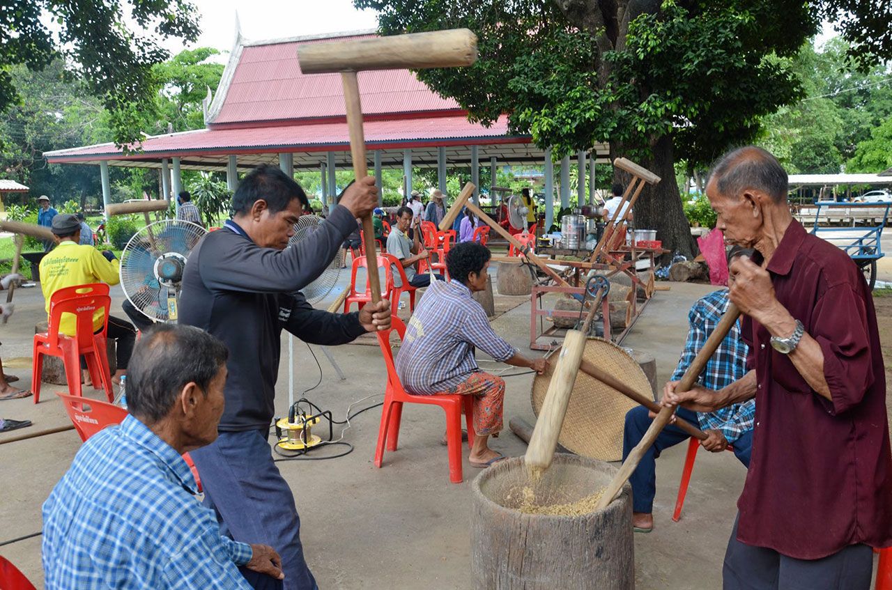 ชาวบ้านช่วยกันตำข้าวเหนียวเพื่อแปรสภาพเป็นข้าวเม่า นำไปทอดขายนักท่องเที่ยวนำเงินบำรุงวัด.