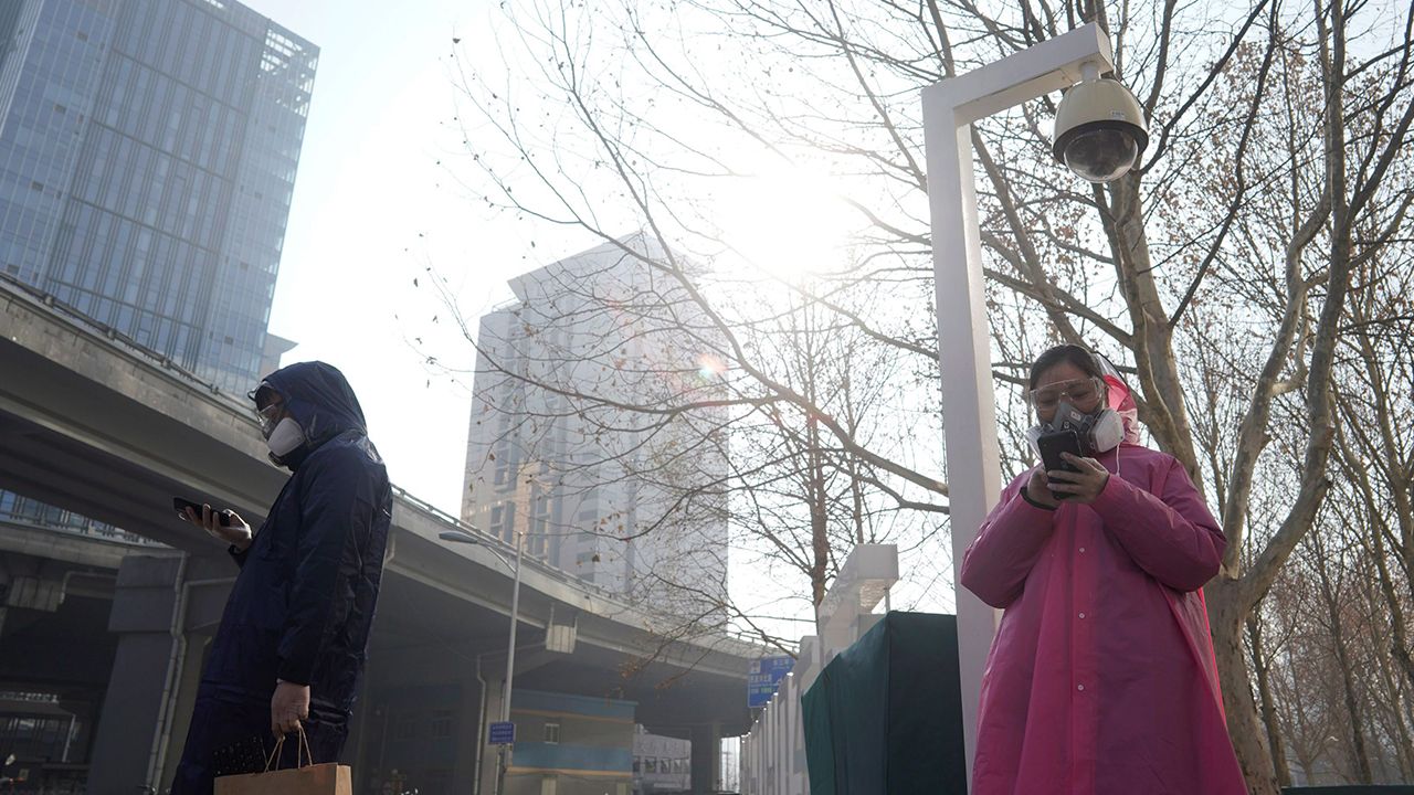 ตรวจเข้ม–ชาวจีนสวมหน้ากากอนามัยยืนใต้กล้องโทรทัศน์วงจรปิดขณะรอข้ามถนนในกรุงปักกิ่ง เมื่อ 10 ก.พ. หลังช่วงวันหยุดยาวเทศกาลตรุษจีน ซึ่งถูกขยายเวลาออกไปอีก 10 วัน เพื่อควบคุมการระบาดของไวรัสโควิด–19 (รอยเตอร์)