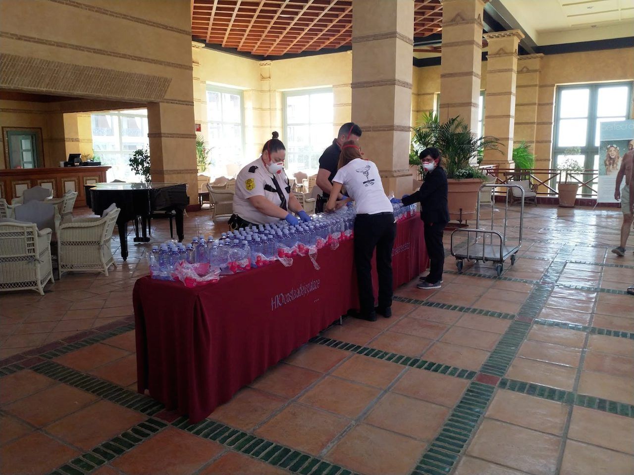 เจ้าหน้าที่โรงแรม เอช10 ฯ สวมหน้ากากอนามัยจัดเตรียมขวดน้ำสำหรับแขกที่ล็อบบี้