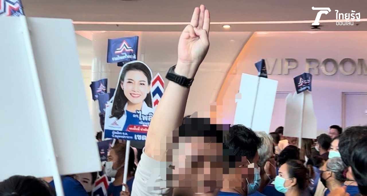 วัยรุ่นชายคนหนึ่งเดินเข้ามาทางประตู พร้อมกับยกมือชูสัญลักษณ์ 3 นิ้ว ท่ามกลางกองเชียร์ “ลุงตู่” ที่มารอส่ง พล.อ.ประยุทธ์ ที่เมืองทองธานี