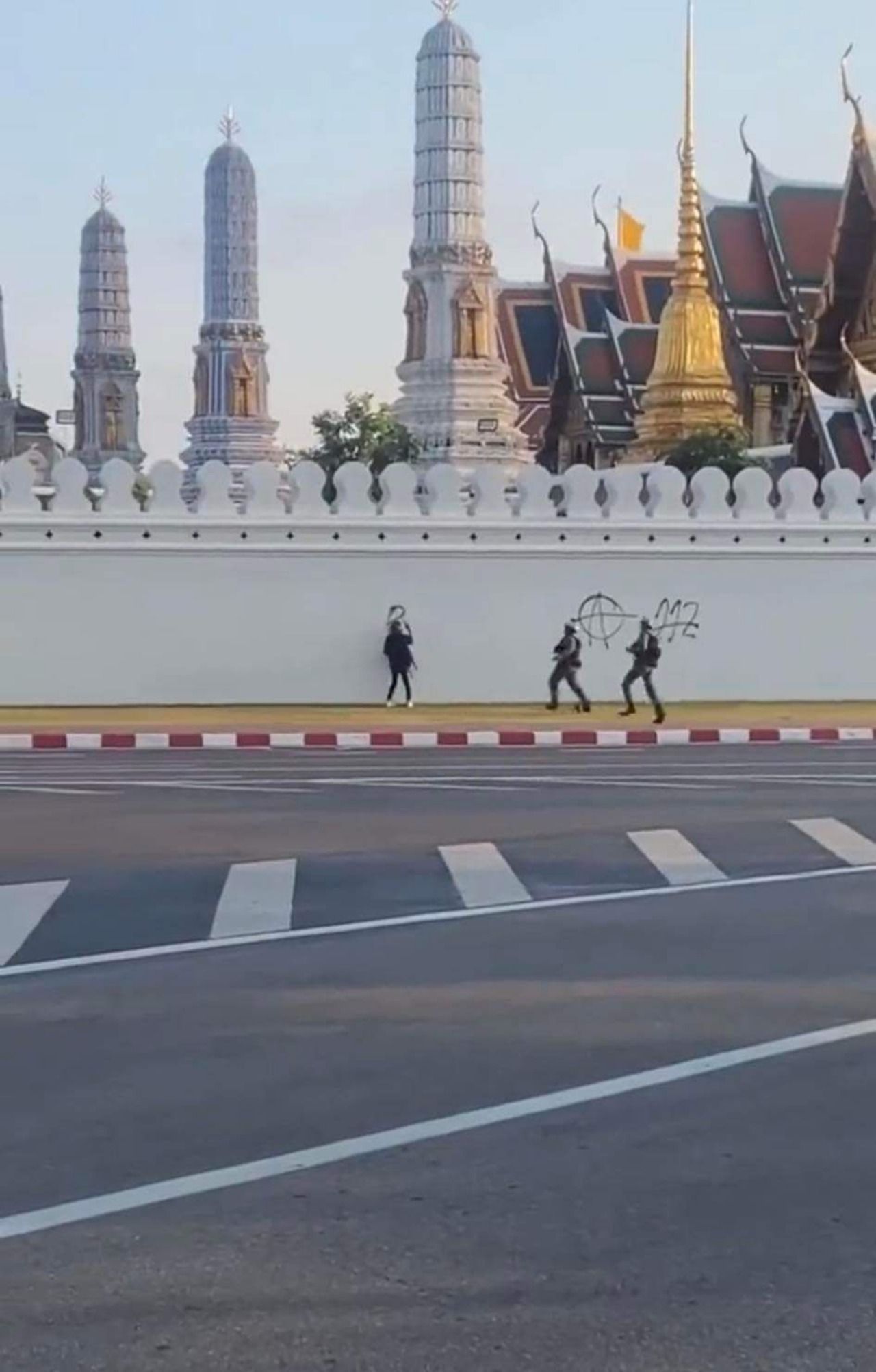 ชายรายหนึ่งกำลังพ่นสีสเปรย์ลงบนกำแพงพระบรมมหาราชวัง