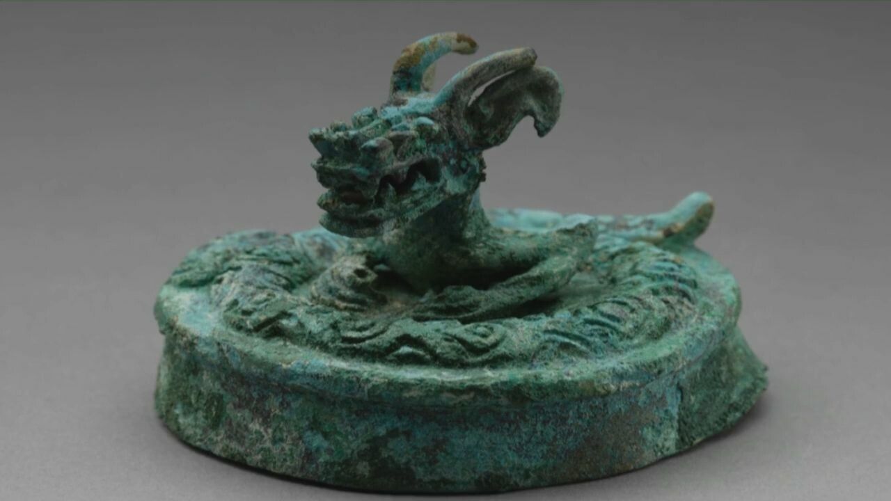 ฝาภาชนะสัมฤทธิ์ถูกพบในหลุมบูชายัญหมายเลข 3 ในซากโบราณสถานซานซิงตุย