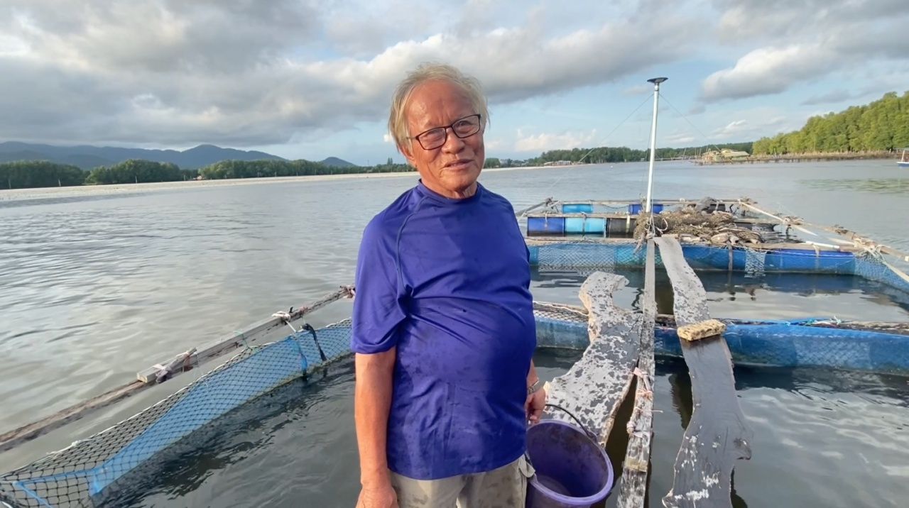 ลุงถนอมกับกระชังที่เลี้ยงปลา