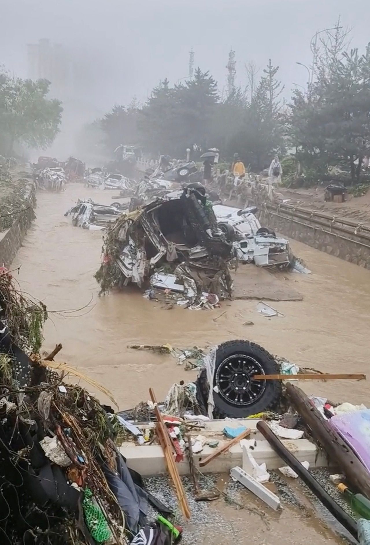 รถยนต์ในเขตเหมินโถวโกว ในกรุงปักกิ่ง ถูกกระแสน้ำท่วมซัดจนมากองรวมกันได้รับความเสียหายอย่างหนัก