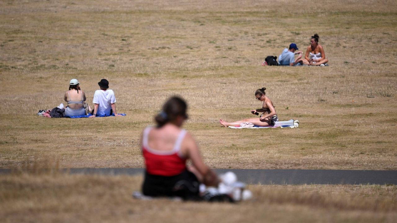 ผู้คนออกมาอาบแดด บนสนามหญ้าในสวนสาธารณะกรีนวิช ในกรุงลอนดอน เมื่อ 16 ก.ค. 65  ขณะที่สหราชอาณาจักรกำลังเผชิญกับสภาพอากาศร้อนจัด จากอิทธิพลคลื่นความร้อน