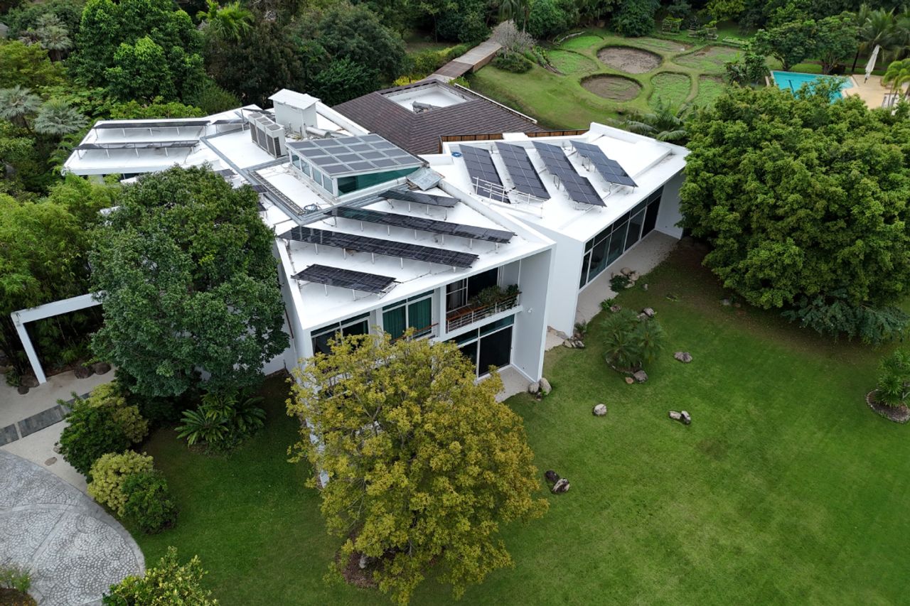 ภาพมุมบนของบ้านพักหลังใหญ่ ด้านหลังเป็นพื้นที่ปลูกพืช และสระว่ายน้ำ