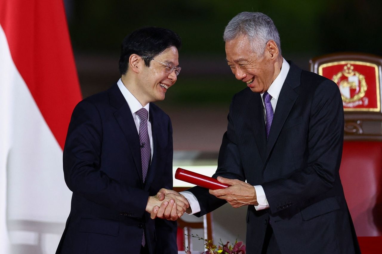 เมื่อวันที่ 15 พฤษภาคม 2567 ลี เซียน ลุง (ขวา) จับมือแสดงความยินดี กับ ลอว์เรนซ์ หว่อง หลังสาบานตนเข้ารับตำแหน่งนายกรัฐมนตรี สิงคโปร์ (ภาพ : AFP)