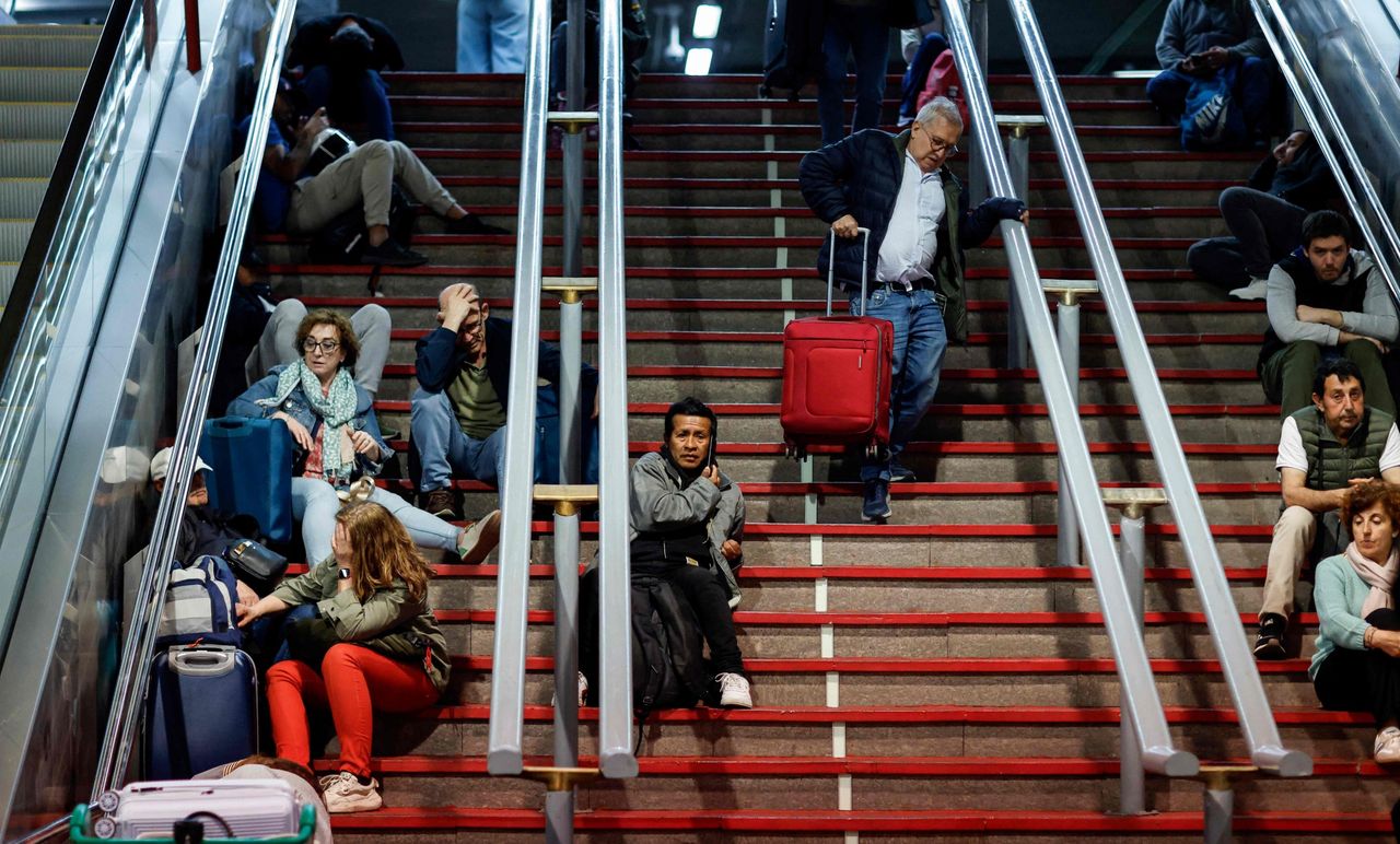 ผู้คนนั่งบนบันไดเพื่อเตรียมตัวพักค้างคืนที่สถานีรถไฟ Atocha ในกรุงมาดริด ประเทศสเปน หลังจากเกิดไฟฟ้าดับครั้งใหญ่