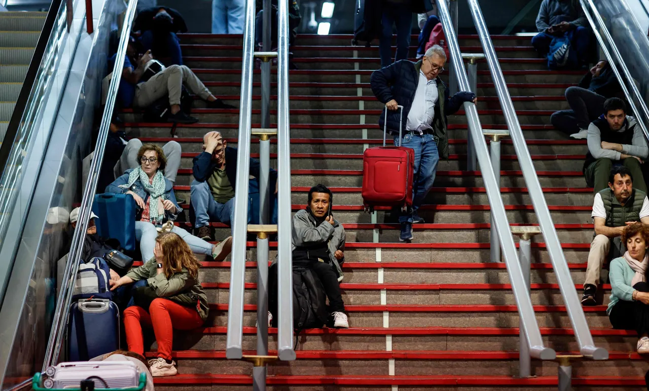 ผู้คนนั่งบนบันไดเพื่อเตรียมตัวพักค้างคืนที่สถานีรถไฟ Atocha ในกรุงมาดริด ประเทศสเปน หลังจากเกิดไฟฟ้าดับครั้งใหญ่