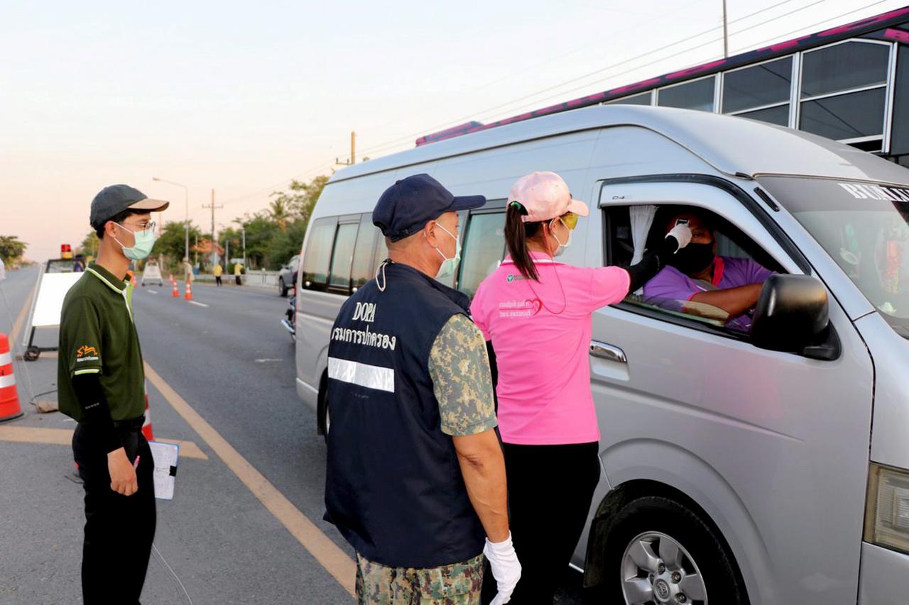 เจ้าหน้าที่ประจำจุดคัดกรองใน จ.อ่างทอง ตรวจวัดอุณหภูมิผู้ขับขี่รถยนต์ทุกคันรวมทั้งคนในรถทุกรายอย่างเข้มงวด เพื่อป้องกันการแพร่ระบาด.