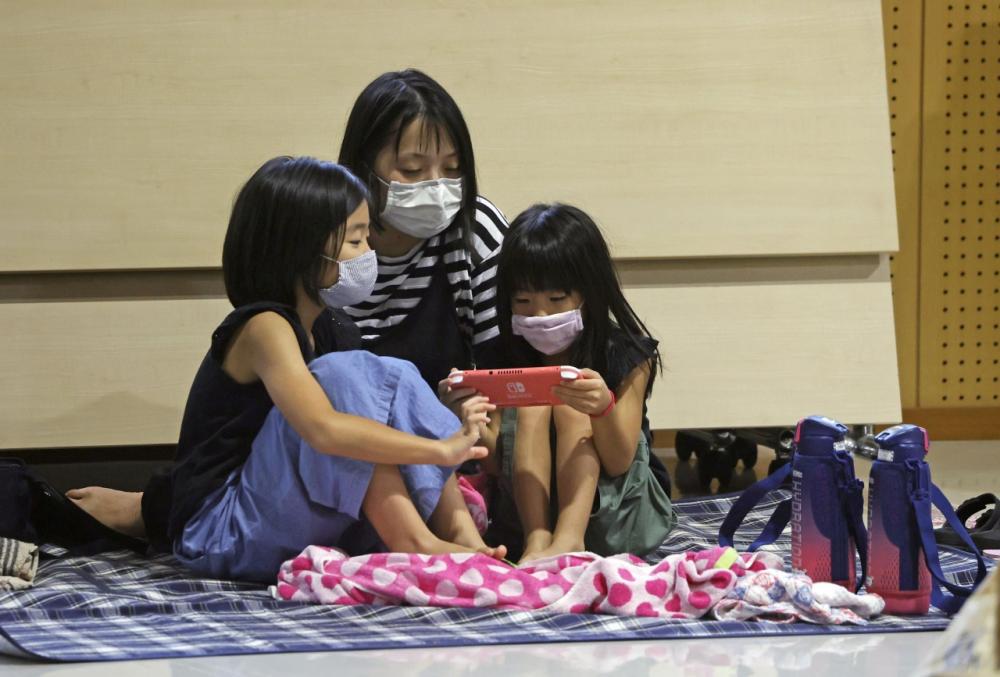 หญิงชาวญี่ปุ่นและลูกสาวสองคน อพยพมาอยู่ในศูนย์พักพิงชั่วคราว เพื่อความปลอดภัย ขณะซุปเปอร์ไต้ฝุ่น ไห่เฉิน ถล่มภาคใต้ของประเทศ