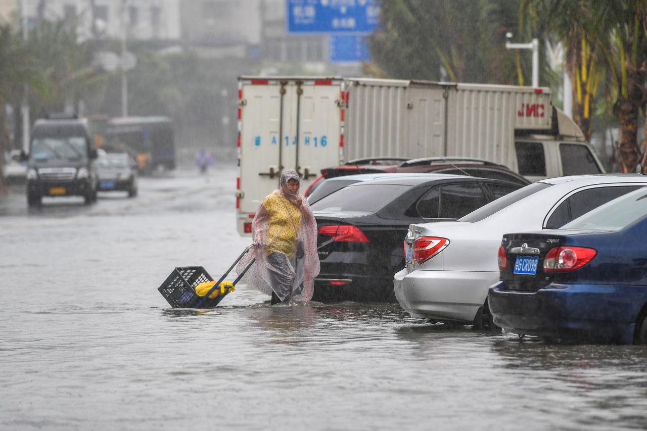 ชาวจีนในมณฑลไห่หนาน หรือไหหลำ เดินลุยน้ำท่วมถนน ขณะเกิดฝนตกหนัก จากอิทธิพลของพายุโซนร้อนวิภา เมื่อ 1 ส.ค.62