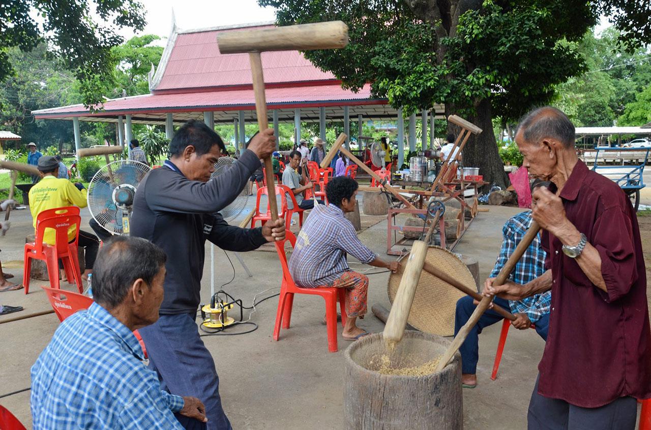 ชาวบ้านช่วยกันตำข้าวเหนียวเพื่อแปรสภาพเป็นข้าวเม่า นำไปทอดขายนักท่องเที่ยวนำเงินบำรุงวัด.