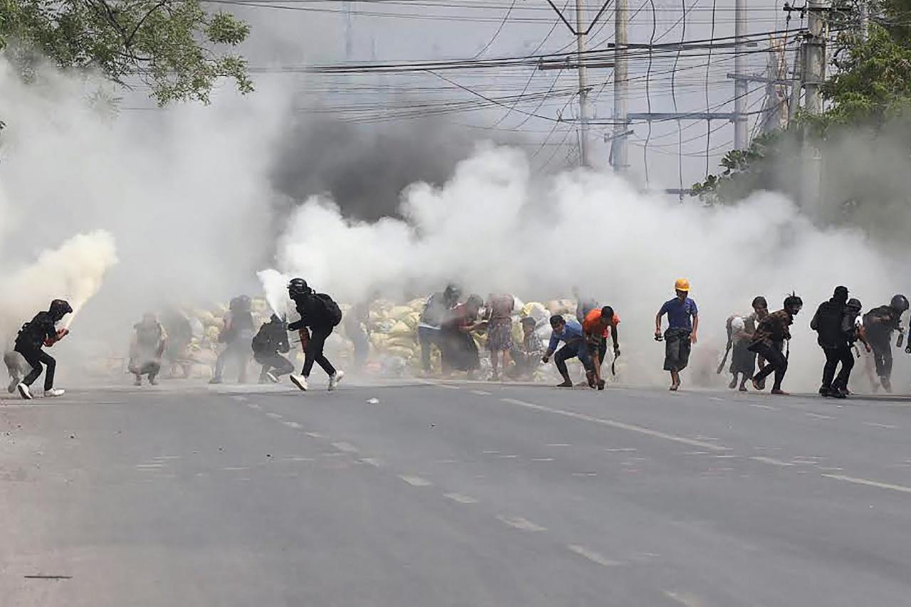 Protesters in Mandalay flee from tear gas fired by officers.  During a rally on March 15, 2021