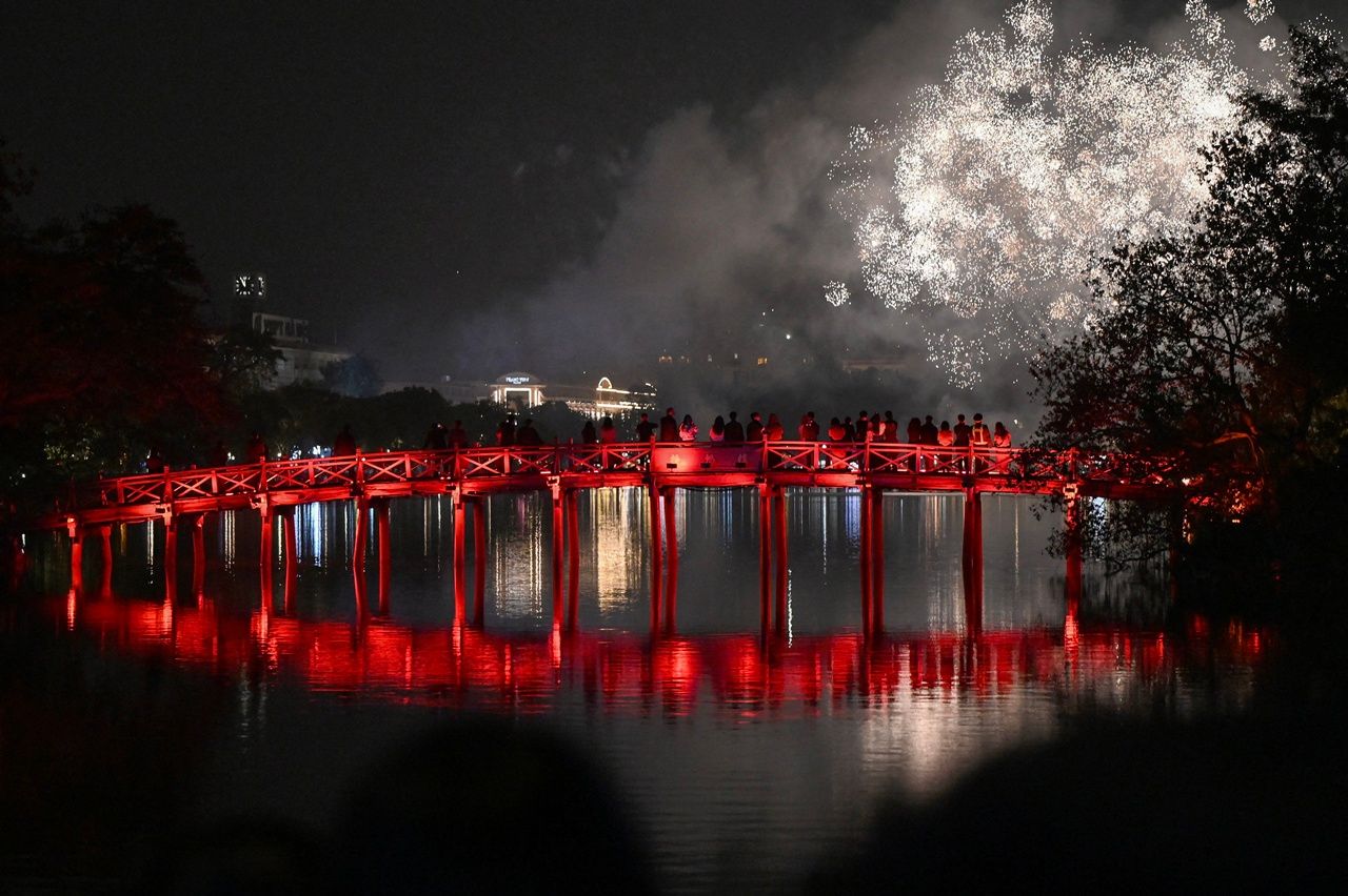 ชาวเวียดนามชมดอกไม้ไฟในคืนส่งท้ายปีเก่าจากบนสะพานเทฮุก ในกรุงฮานอย