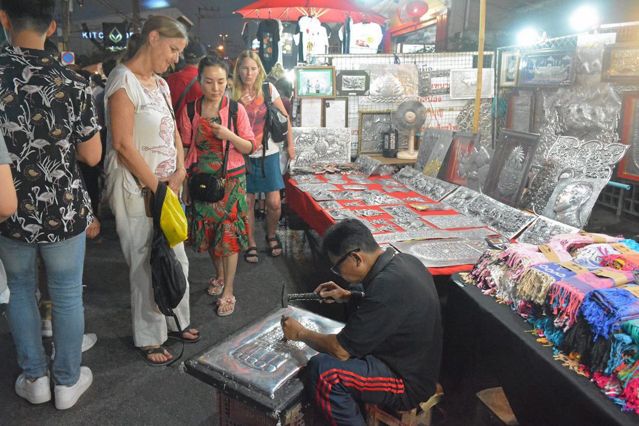 โชว์สลักลวดลายบนแผ่นเงินให้นักท่องเที่ยวชมบนถนนคนเดินวัวลาย.