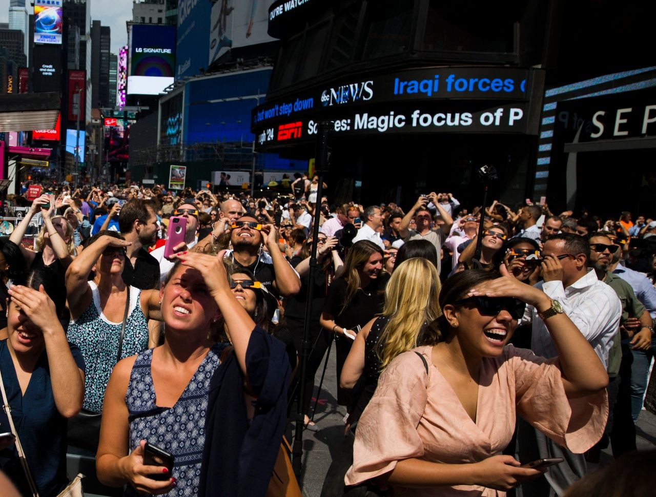 ฝูงชนในนครนิวยอร์ก แสดงความยินดีหลังจากฟ้าเริ่มเปิด แสดงให้เห็นดวงอาทิตย์ที่ถูกดวงจันทร์บดบังไปบางส่วน