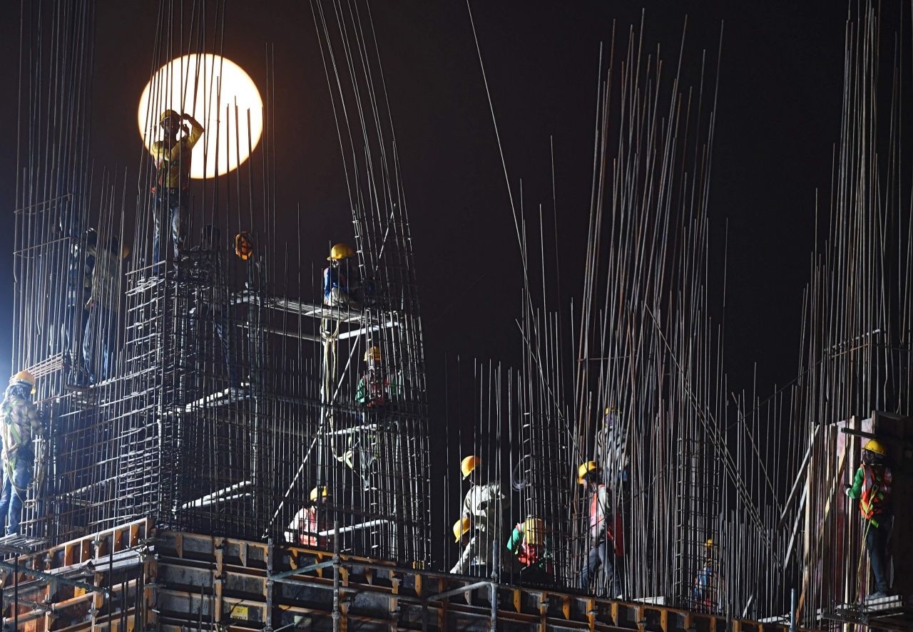 ภาพคนงานก่อสร้างในเมืองโกลกาตา ของอินเดีย กำลังทำงานโดยมีซุปเปอร์มูนเป็นฉากหลัง