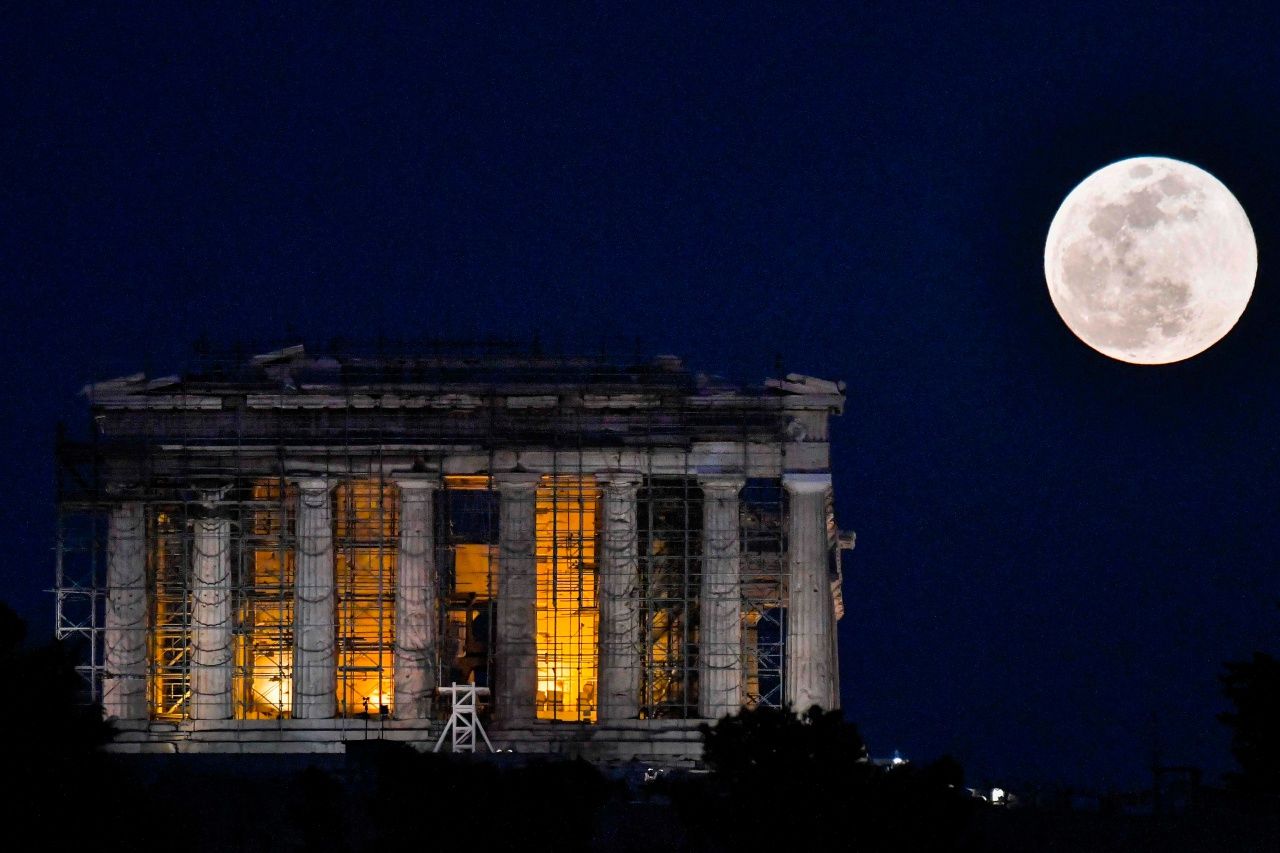 พระจันทร์เต็มดวงลอยอยู่ข้างวิหารพาร์เธนอน ในประเทศกรีซ