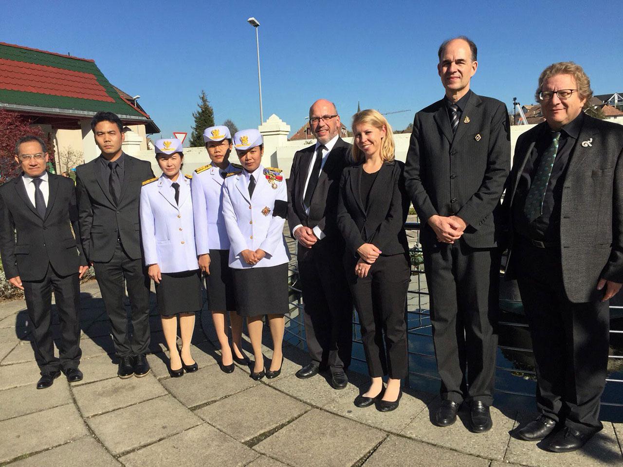 ใจไทย อุปการนิติเกษตร อุปทูต ณ กรุงเบิร์น สวิตเซอร์แลนด์ ถ่ายภาพกับผู้ไปร่วมพิธีถวายดอกไม้จันทน์ในพระราชพิธีถวายพระเพลิงพระบรมศพ พระเจ้าอยู่หัว รัชกาลที่ 9 ที่วัดศรีนครินทรวราราม เมืองเกรทเซนบาค.