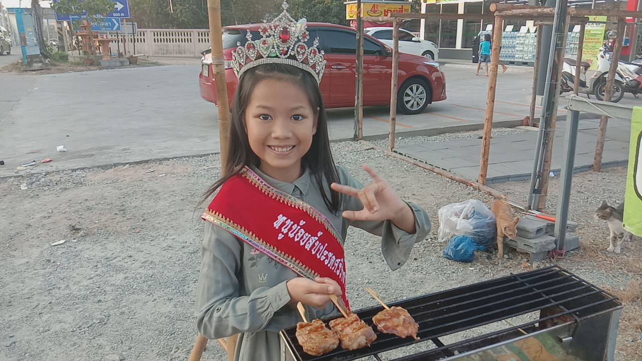 หนูน้อยวัย 10 ขวบสวมมงฯ ขายหมูปิ้ง ริมถนนเมืองชล หารายได้ช่วยครอบครัว